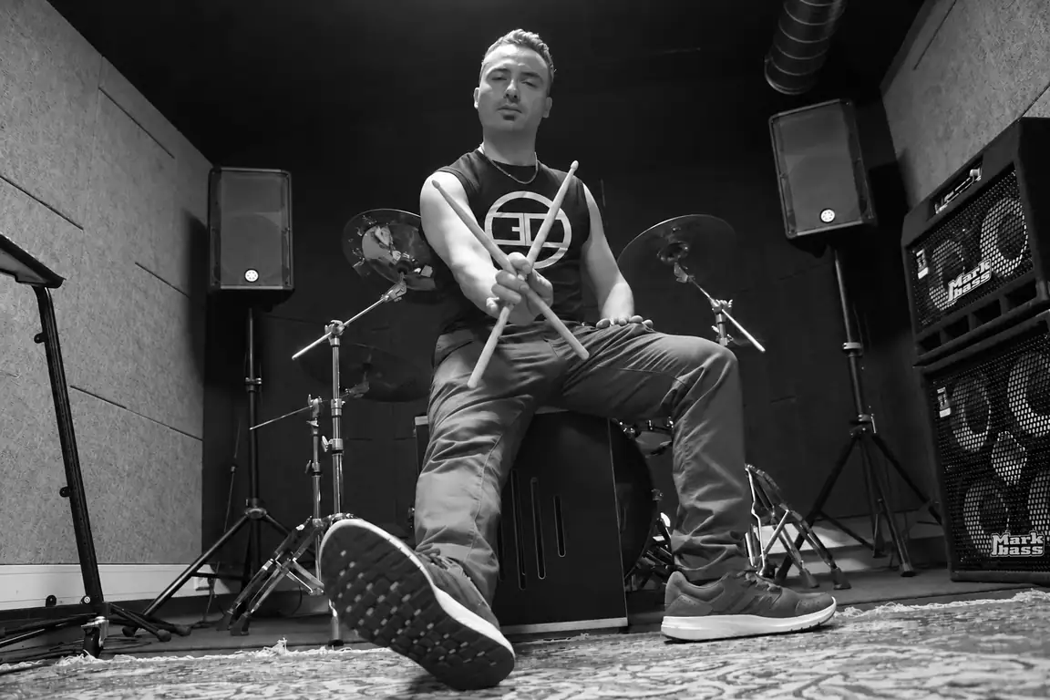 Joel seated at the drums, holding drumsticks
